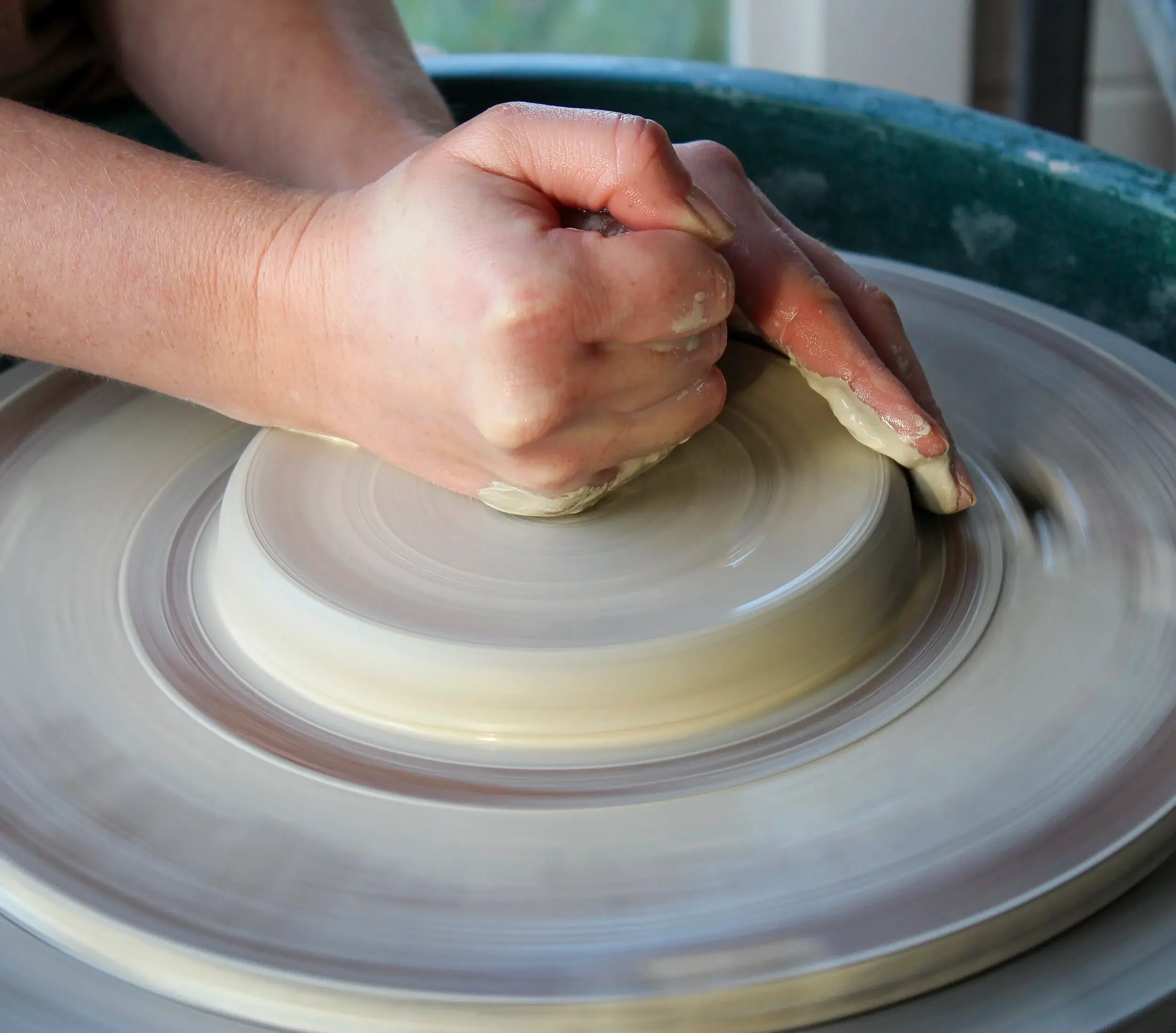 Hands of an artisan making a choice between different glaze test tiles.