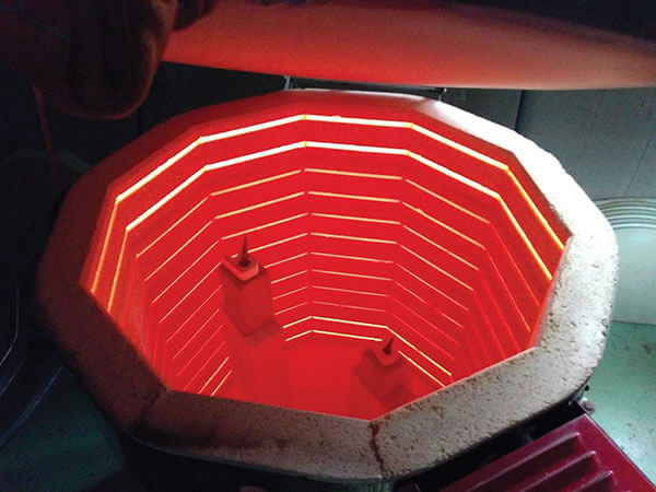 Interior of a hot kiln with glowing ceramic pieces.