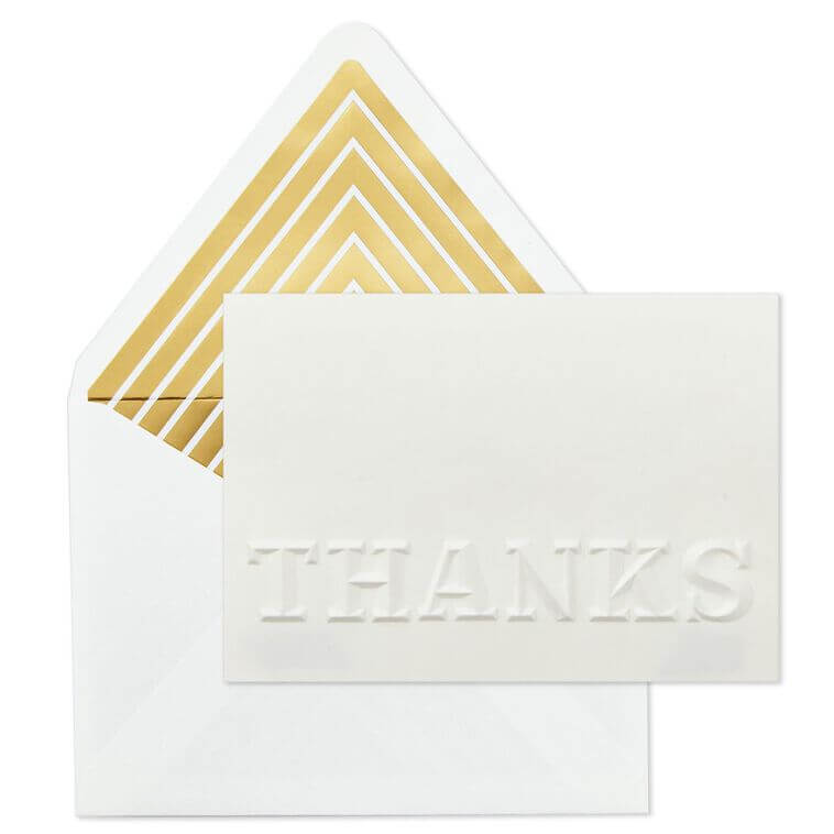 A hand stamping a card with a 'Thank You' message to be included in a gift box.