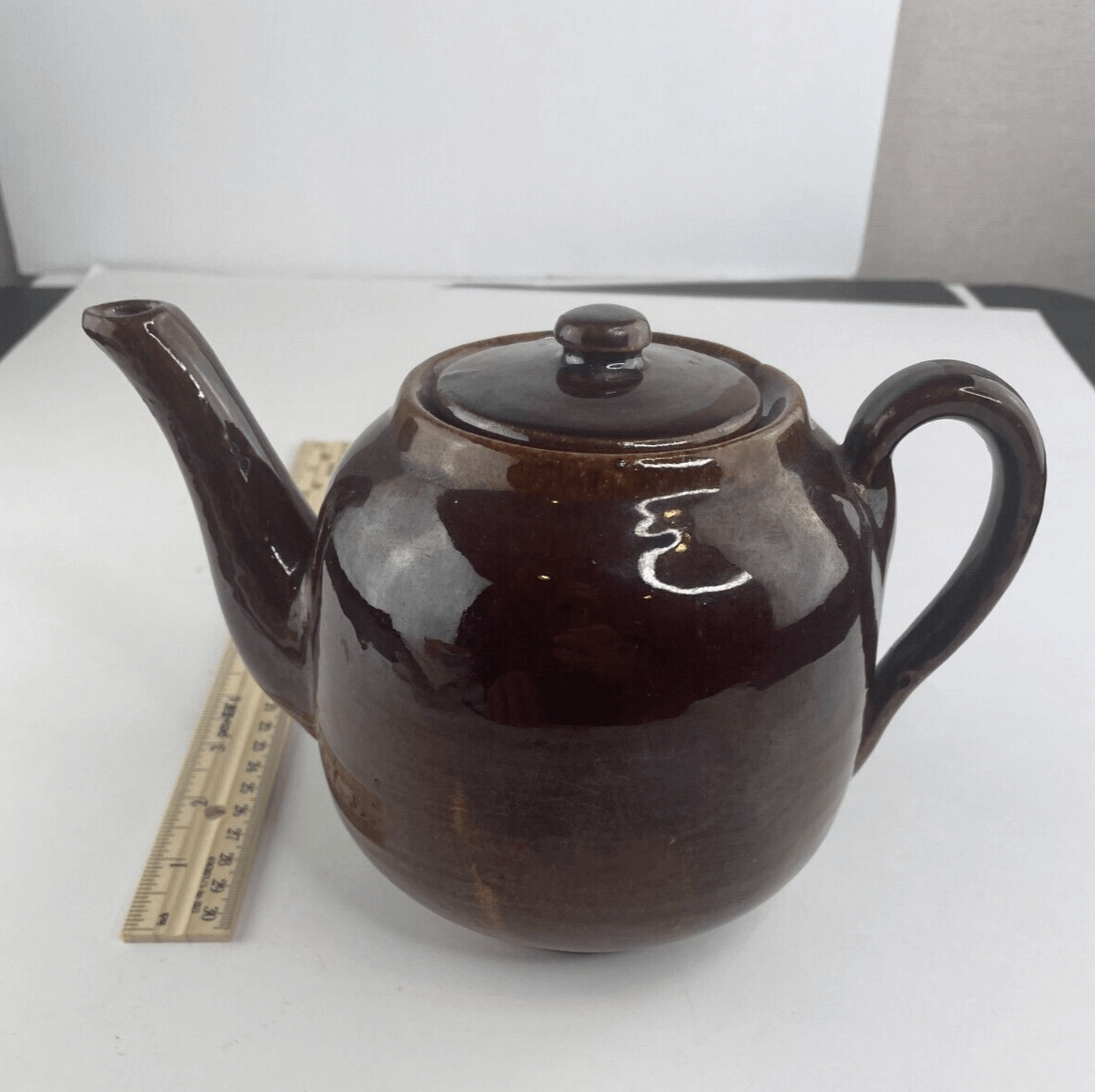 An artisan carefully inspecting a finished teapot for quality.